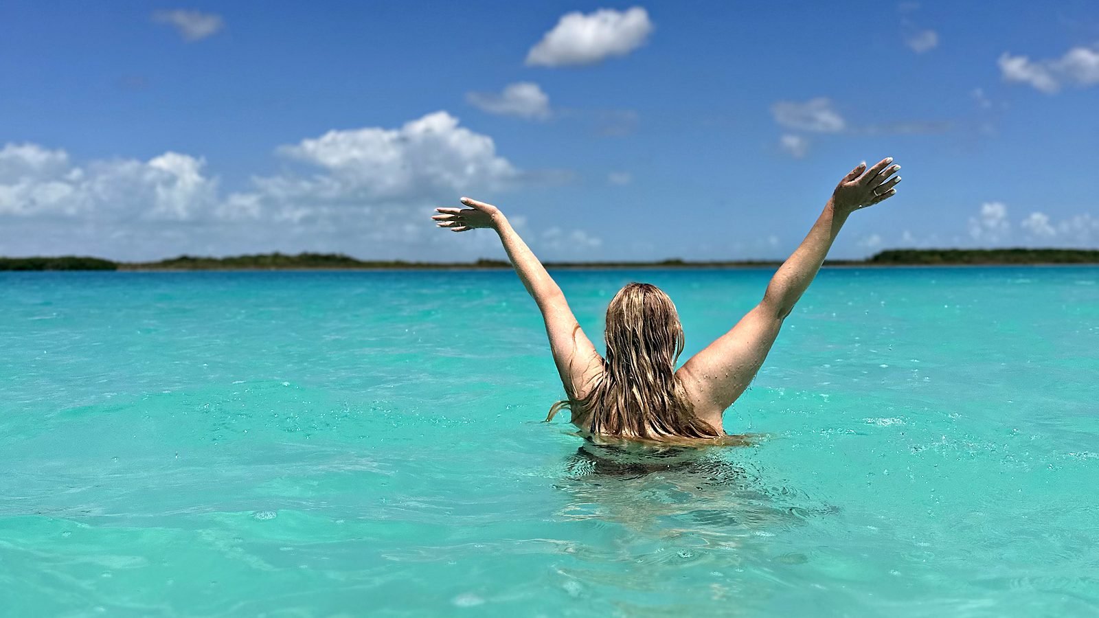 Una persona de pie en el agua turquesa de la Laguna de Bacalar